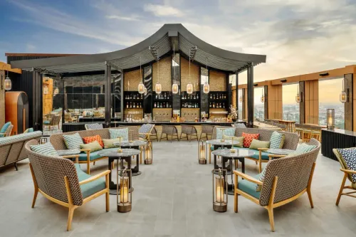 Warmly-Lit Thai Rooftop Bar With Rattan Accents and Skyline-To-Mountain Views for Sunset Networking