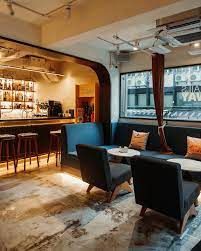Bright Arch-Framed Café Bar With Striped Timber Panelling and Elliptical Mirrors for Mixers and Launches